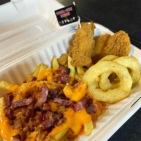 Loaded fries with nacho cheese sauce and bacon with onion rings and chicken strips